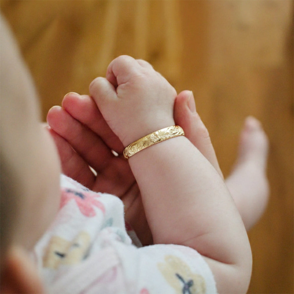 ゴールドのベビーバングルブレスレットを着けた赤ちゃん