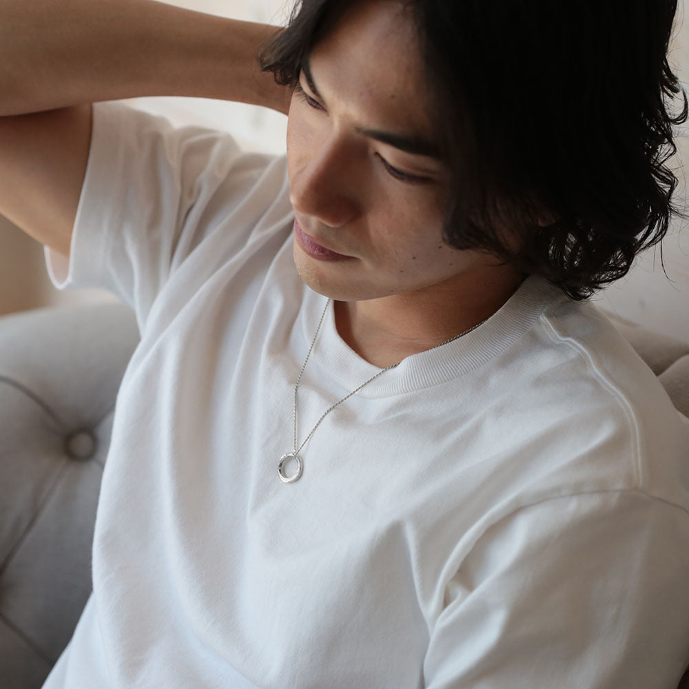 プラチナのメビウスの輪ネックレスを着けた男性の横顔